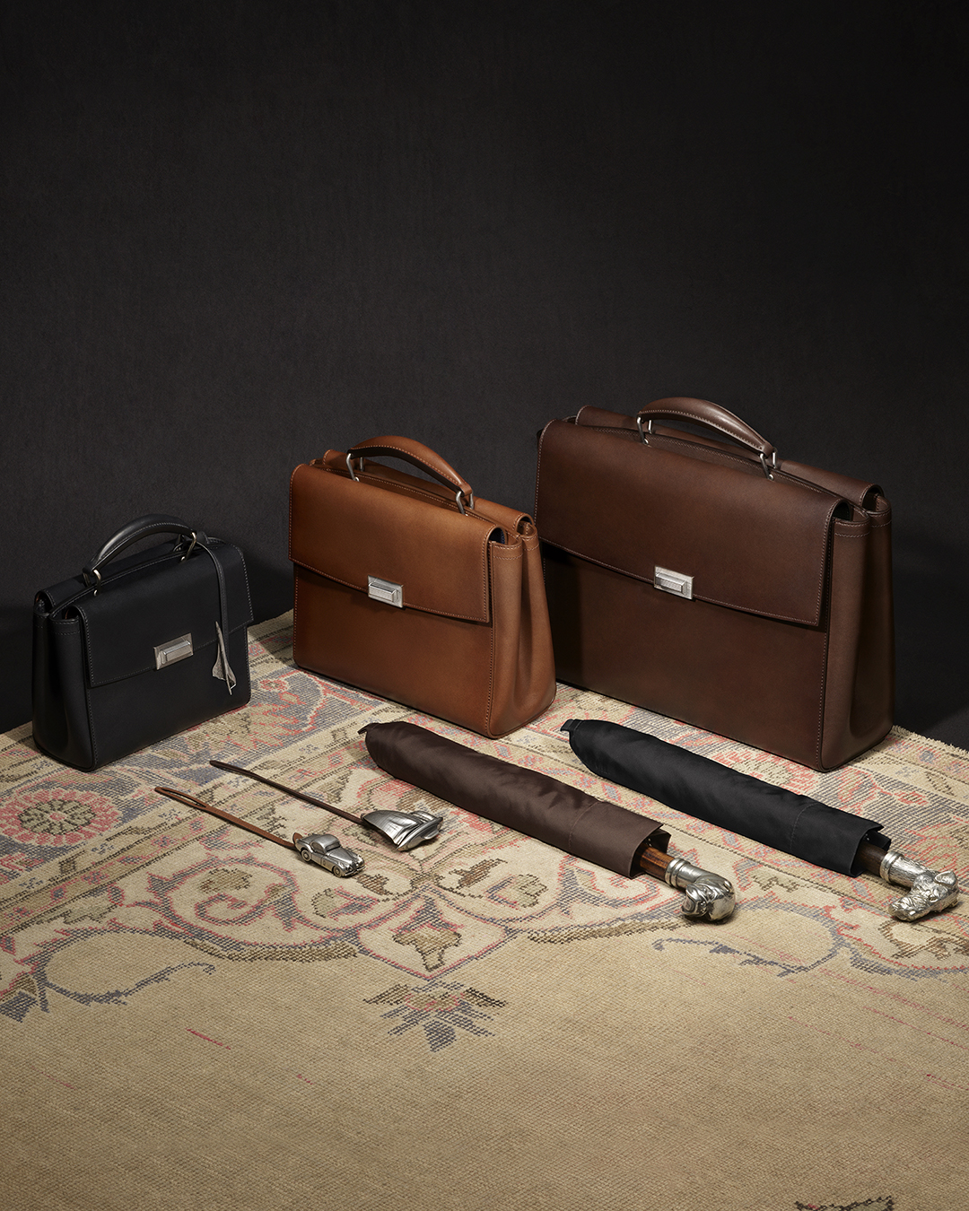 Black, tan and brown Dunhill leather briefcases arranged together.